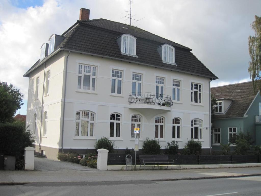 a large white building with a black roof at Patriciavilla tæt på centrum in Haderslev