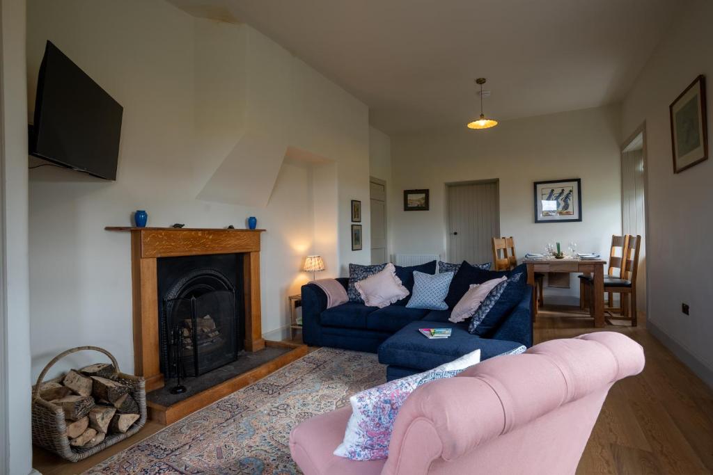 a living room with a blue couch and a fireplace at Skinnel Cottage in Kirkcudbright
