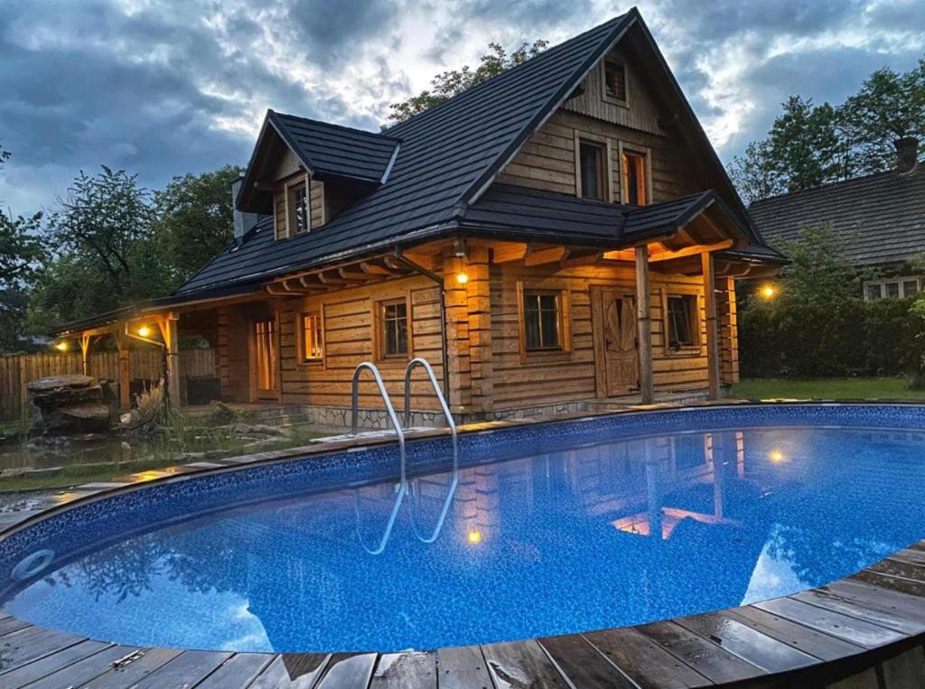 a log cabin with a swimming pool in front of a house at Zacisze Pod Lipą in Andrychów