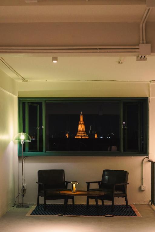 a room with two chairs and a table and a window at Arunne in Bangkok Yai