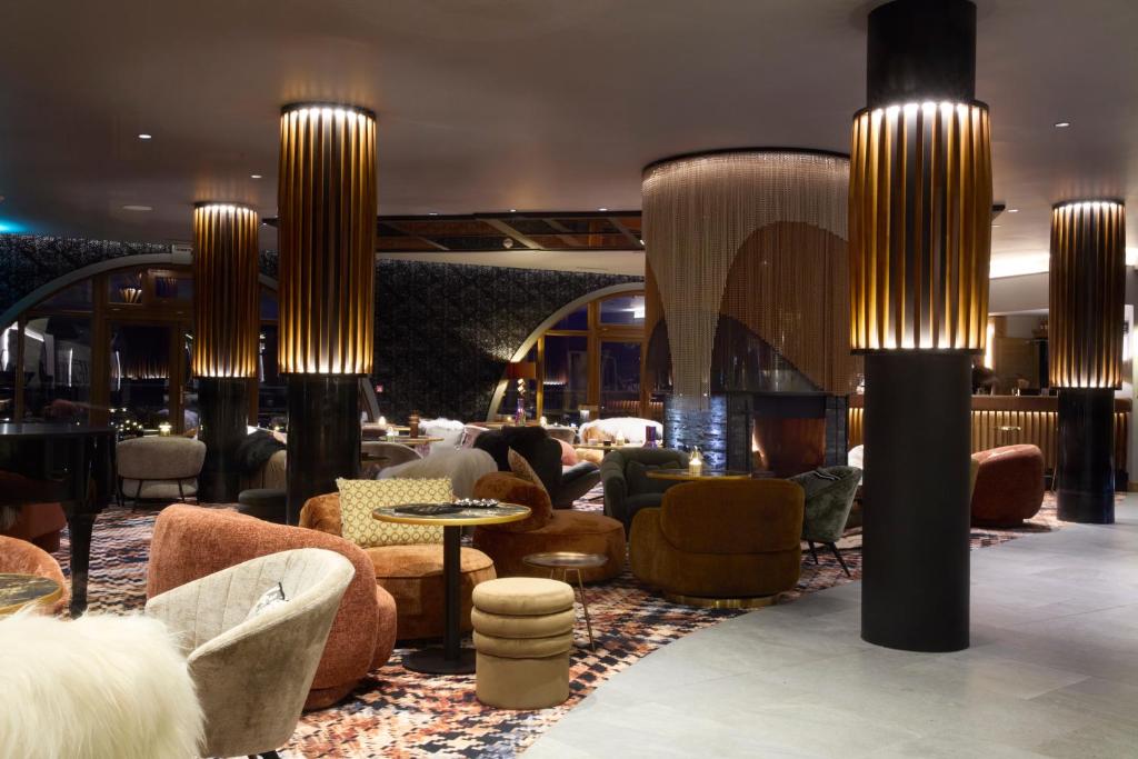 a hotel lobby with chairs and tables and chandeliers at Hôtel Koh-I Nor by Les Etincelles in Val Thorens