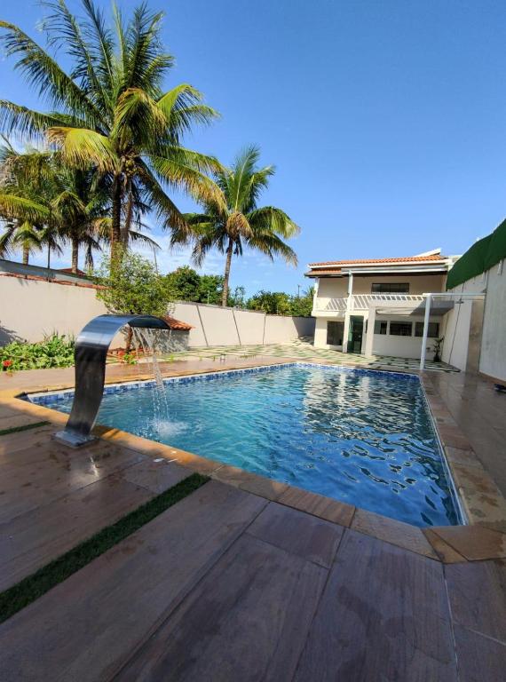 a swimming pool with a fountain in front of a house at Paraiso Particular Piscina e Ar Condicionado in Americana