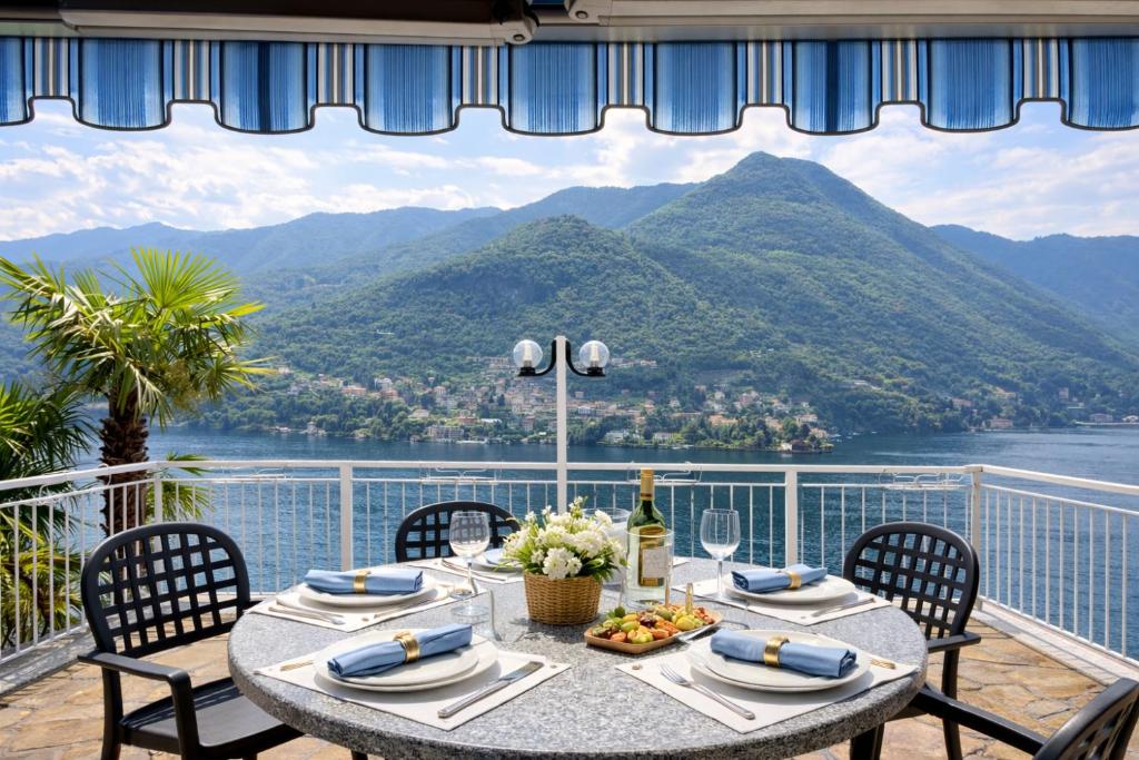 a table on a balcony with a view of the mountains at Villa Fantastica in Carate Urio