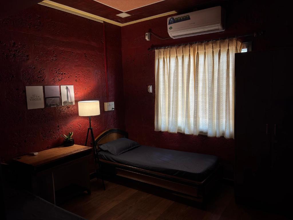 a small room with a bed and a window at Mangalmurti Farmstay in Pendur