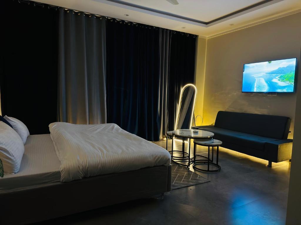 a bedroom with a bed and a couch and a tv at Stay Premium in Islamabad