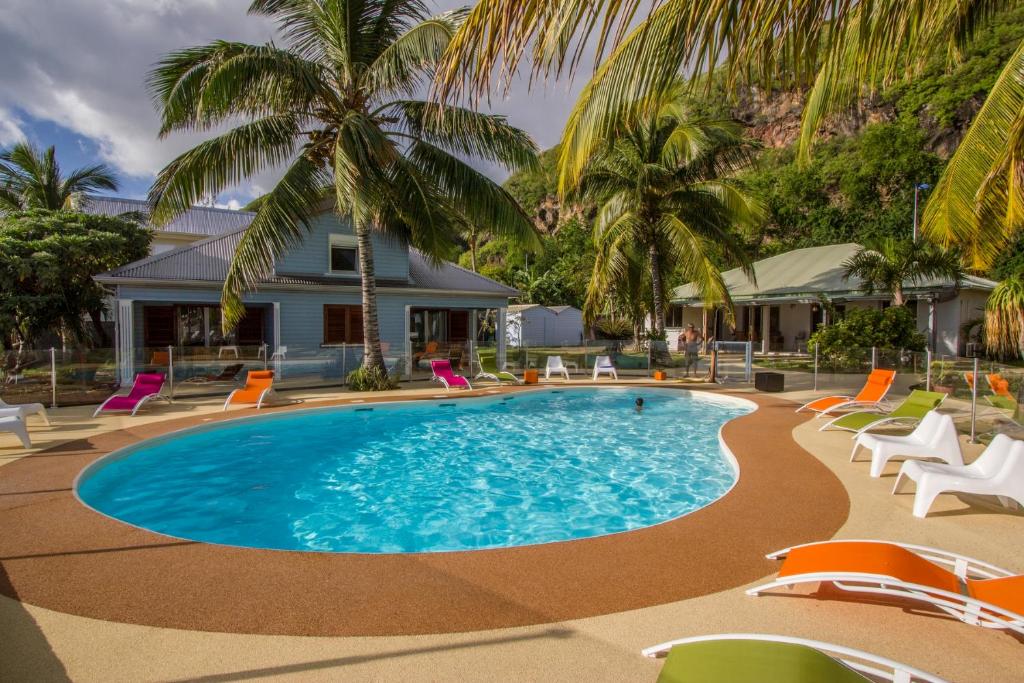 a swimming pool with chairs and palm trees at Leu Pied Dans L&#39;Eau in Saint-Leu