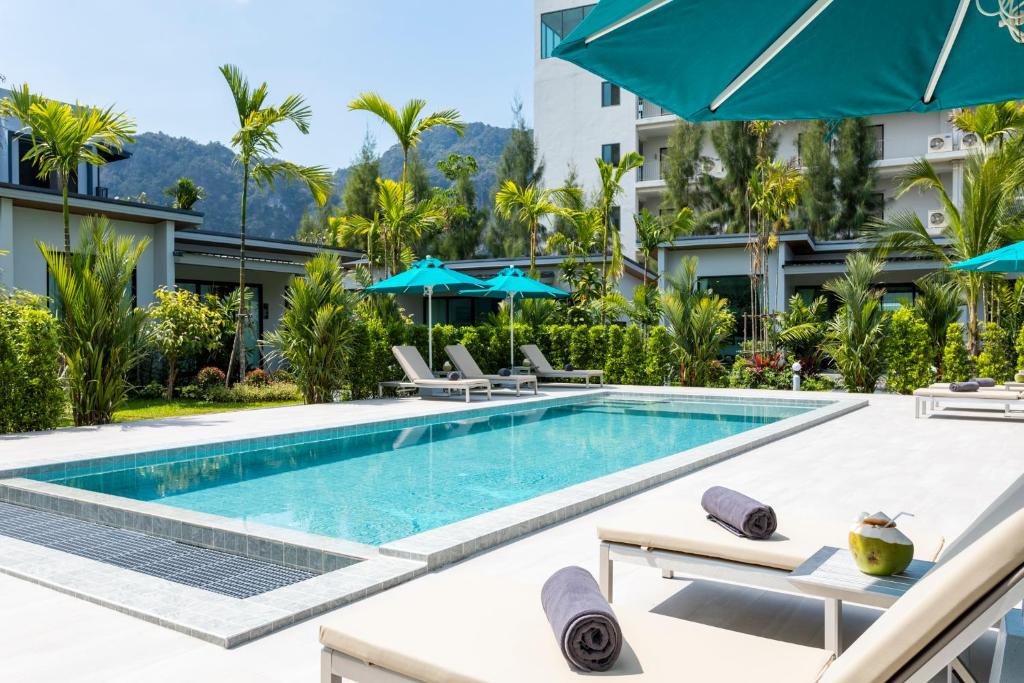 a pool at a hotel with chairs and umbrellas at Nanuea Village Ao Nang in Ao Nang Beach