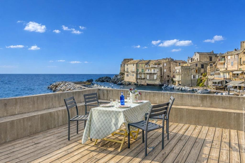 a table and chairs on a deck with a view of the ocean at L'Ortu - maison charmante vue mer - Erbalunga in Erbalunga