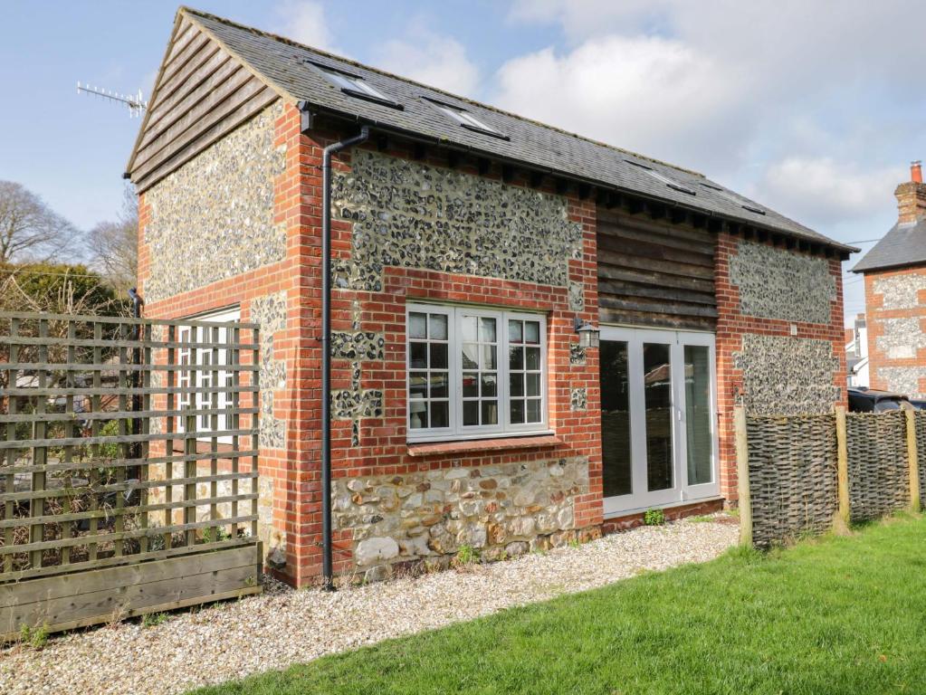 a brick cottage with a window and a fence at The Barn at Myrtle Cottage in Marlborough