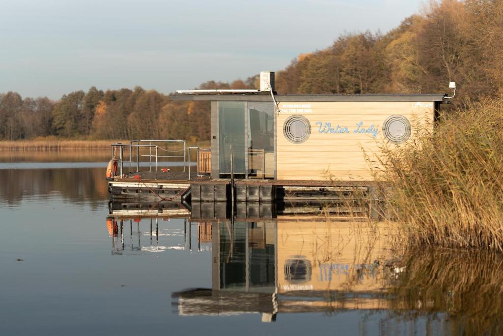 a house on a dock on a body of water at Houseboat Pałuki in Sobiejuchy