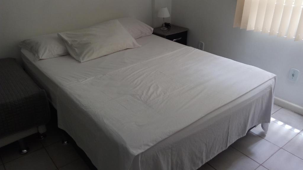 Una cama con sábanas blancas y almohadas en un dormitorio en Copacabana Studio One, en Río de Janeiro