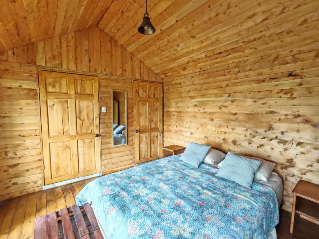 a bedroom with a bed in a wooden cabin at Cabaña Ardilla Corralillo in Corralillo