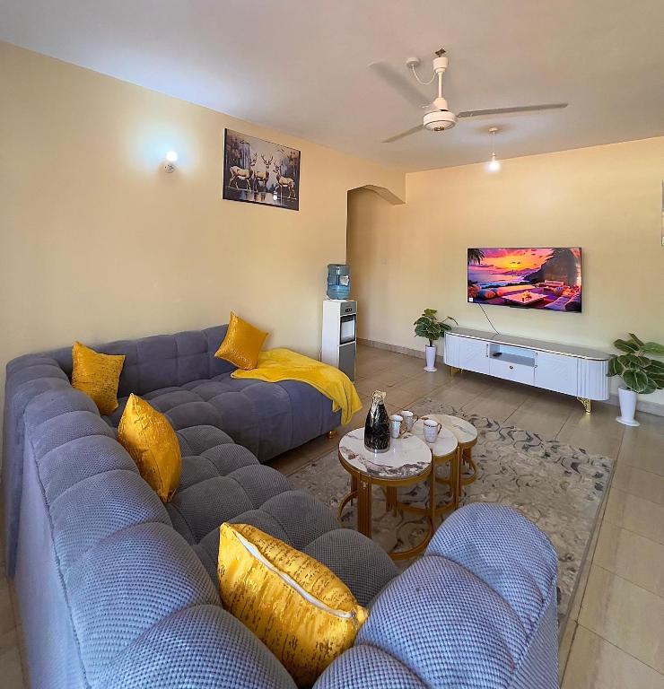 a living room with a blue couch and yellow pillows at COZY Two BEDROOM in Bamburi