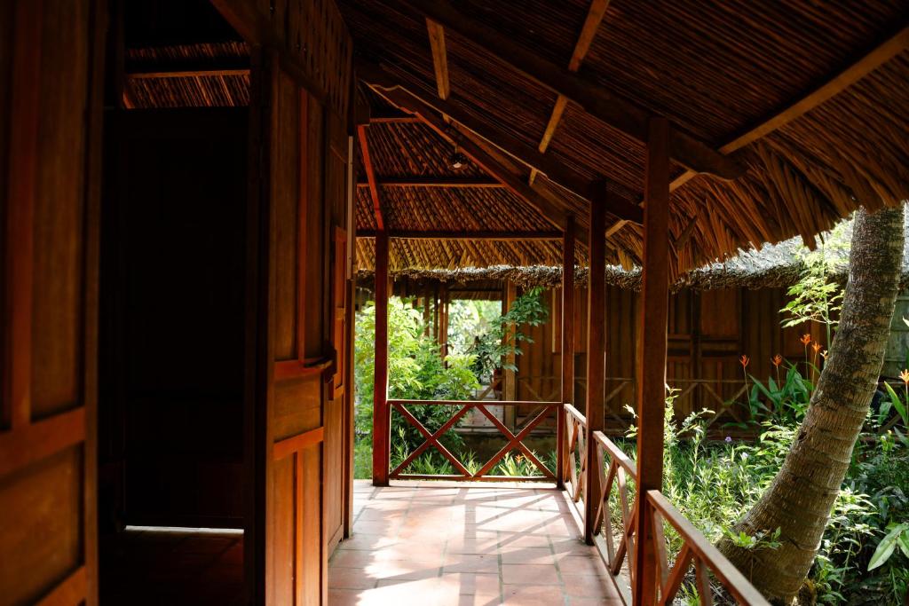 a walkway leading to a building with a straw roof at Le Mékong Vert Ecolodge in Ben Tre