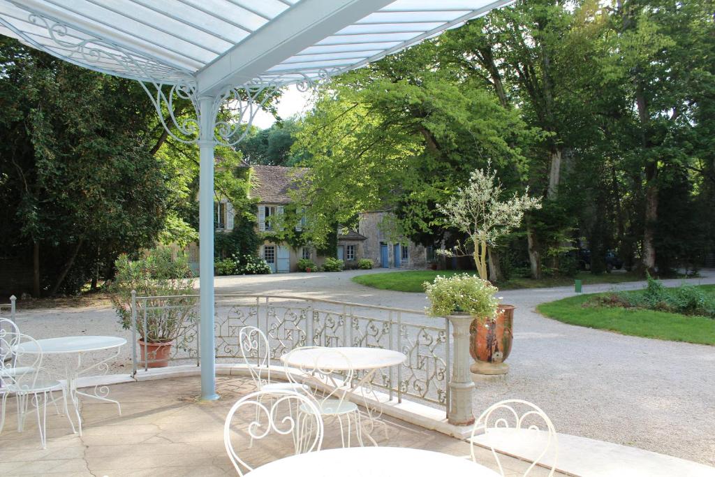 un patio con mesas y sillas bajo una pérgola blanca en Château de tailly en Meursault