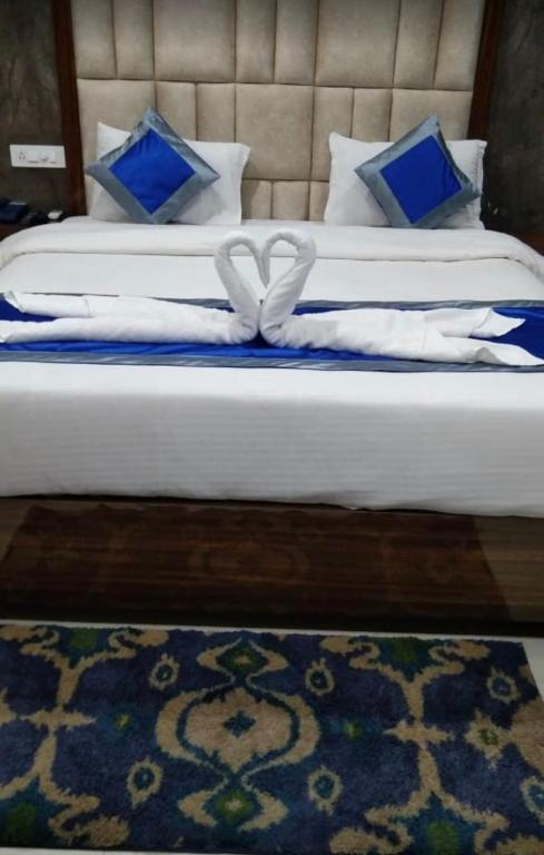 two beds with blue and white pillows and a blue rug at Hotel Tazzodisha Next in Bhubaneshwar