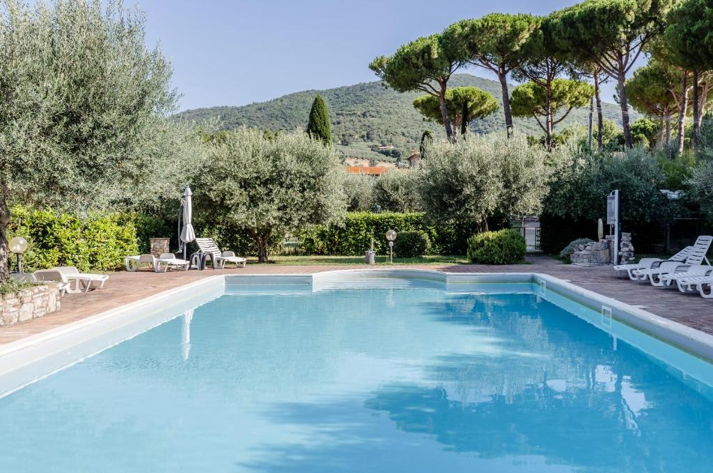 a large swimming pool with blue water in a yard at GuestHost - Lavanda Apartment with Pool & Parking in Passignano sul Trasimeno