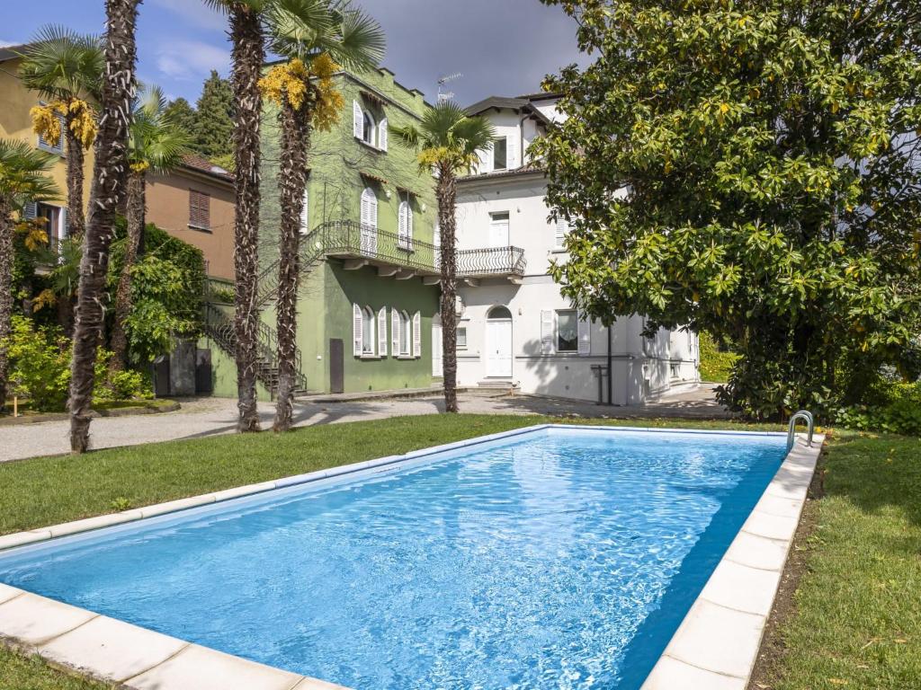 a swimming pool in front of a house with palm trees at Apartment Le Gemme-3 by Interhome in Meina