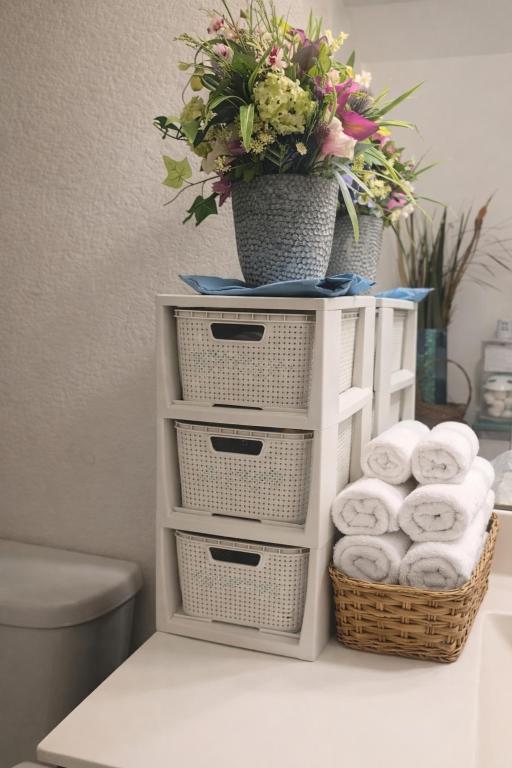 a bathroom shelf with a basket of towels and a vase with flowers at Imani in Manor