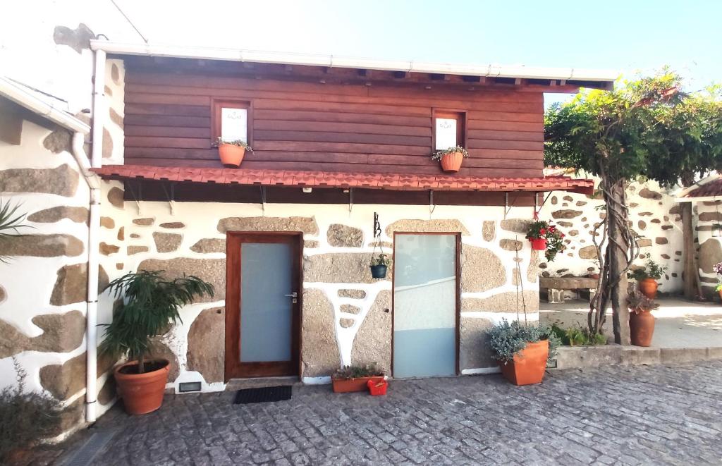 a stone house with two doors and potted plants at CoutoRural in Vila Nova de Gaia