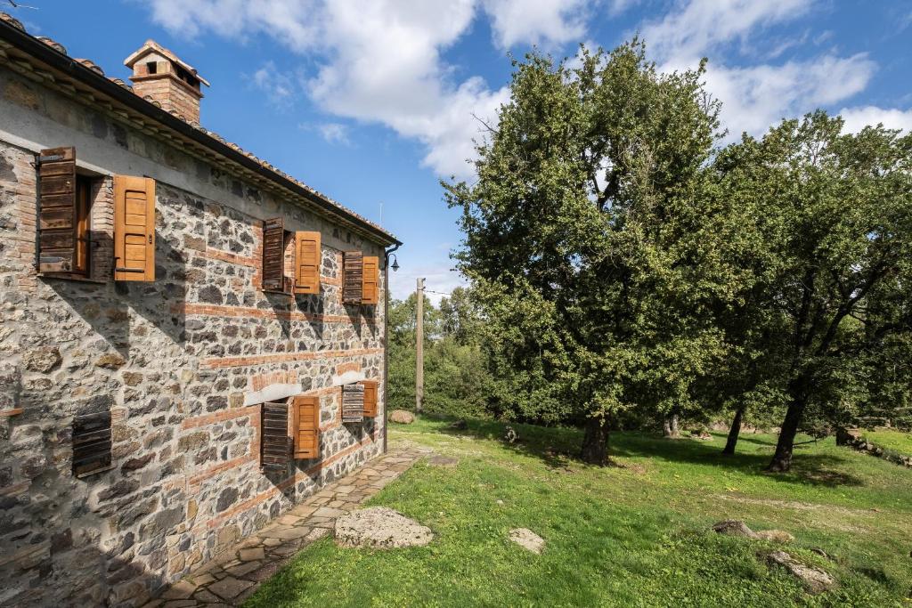 an old stone building with windows and a tree at App.to Colline - Casetta di Ugolino in Radicofani