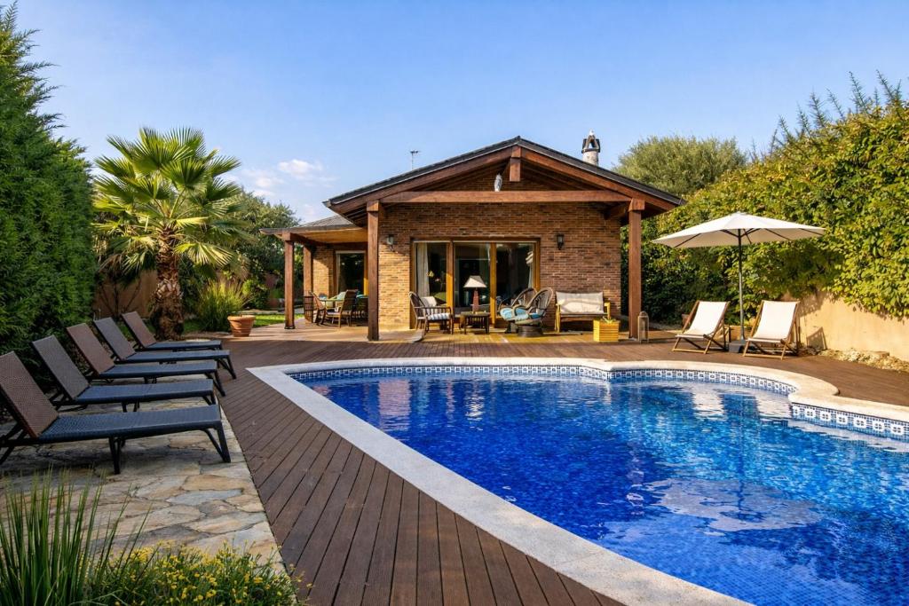 a swimming pool with chairs and a house at Catalunya Casas A Costa Brava gem - only a few minutes to the beach! in Vidreres