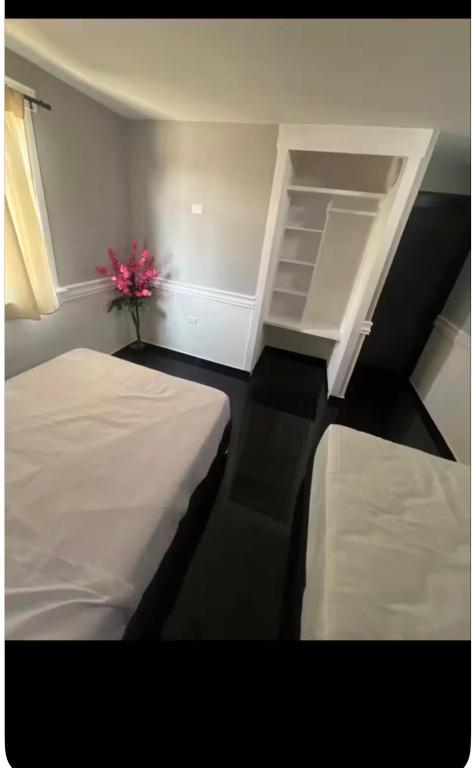 a room with two beds and a vase with a flower at Hospedaje in Cholula