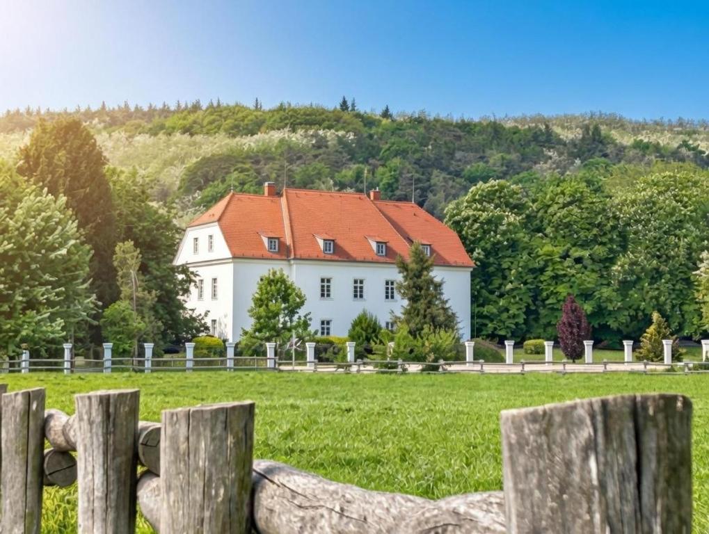 a white house with a red roof in a field at Csillaghy Kastély in Bókaháza