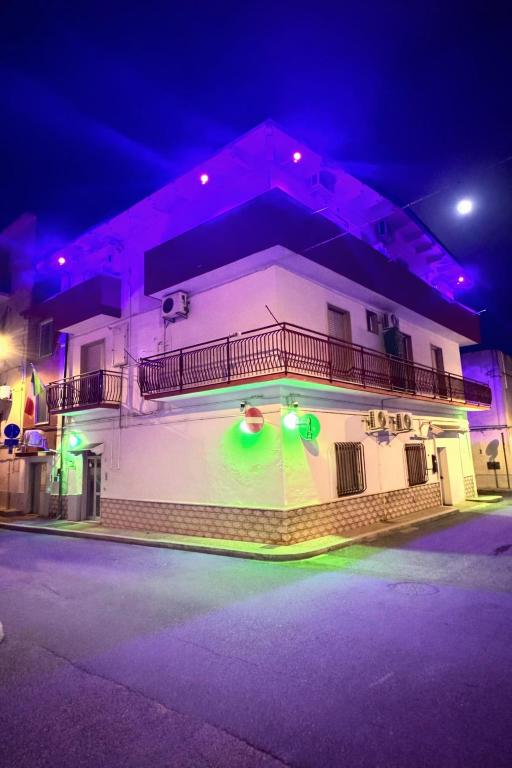a white building with a balcony with green lights at Planet casa vacanze in Montalbano Ionico