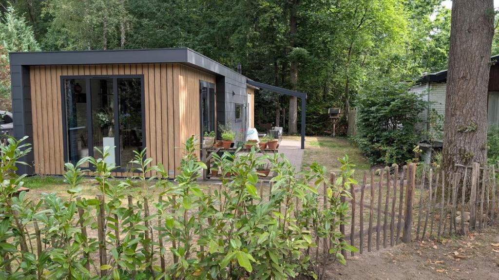 a tiny house in a garden with a fence at Rustige natuur lodge bij Deventer met privé terras in Gorssel