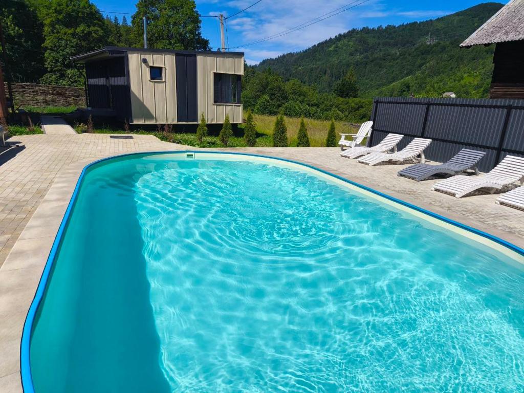 a blue swimming pool with chairs and a house at Славський Двір in Slavske