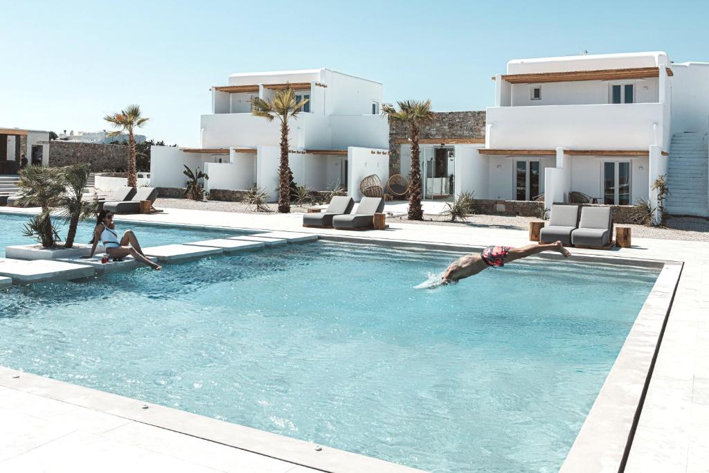 a man diving into a swimming pool in front of a house at Adama Mykonos Boutique Hotel in Mikonos