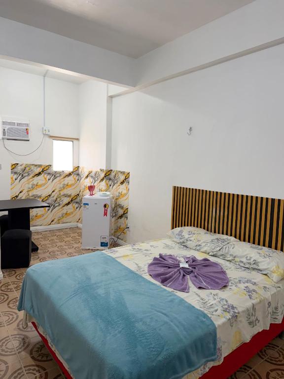 a bedroom with a bed with a blue comforter at Quarto no centro in Manaus