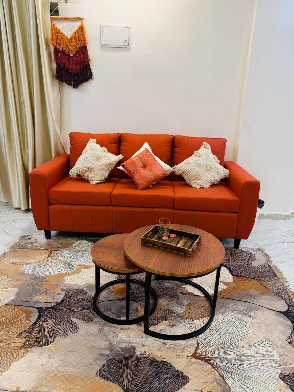a living room with an orange couch and a coffee table at The Hampiness in Hospet