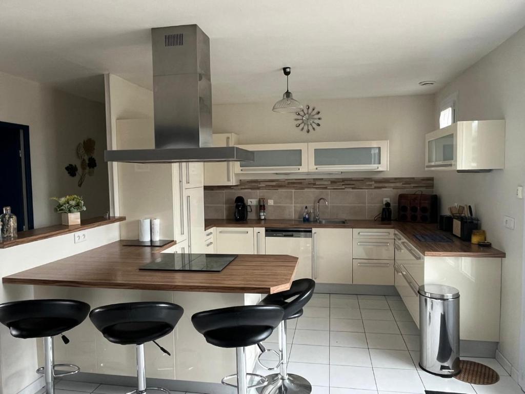 a kitchen with white cabinets and black bar stools at Les camins in Hirel