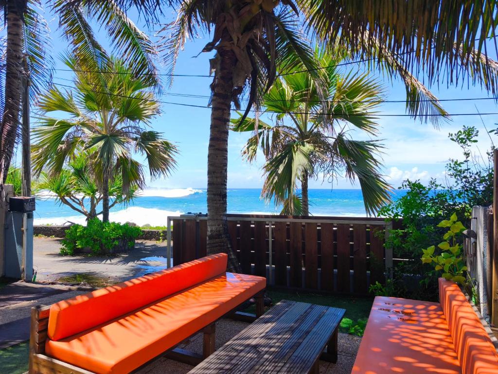 an orange bench sitting next to the beach with palm trees at Maison Bleu-Oxygène Accès direct au bassin Manapany-Les-Bains in Saint-Joseph