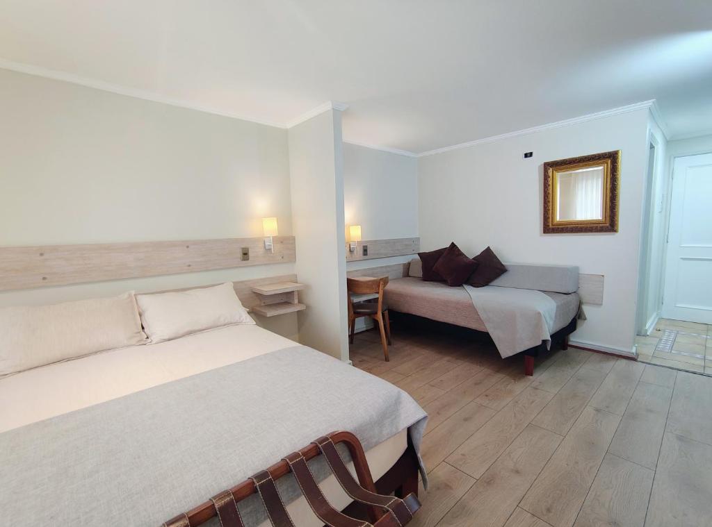 a hotel room with two beds and a couch at Apart Hotel Cambiaso in Santiago