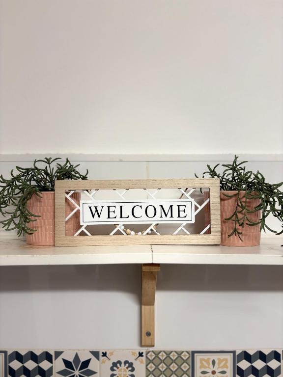 a shelf with potted plants and a welcome sign on it at O Meu Cantinho in Elvas