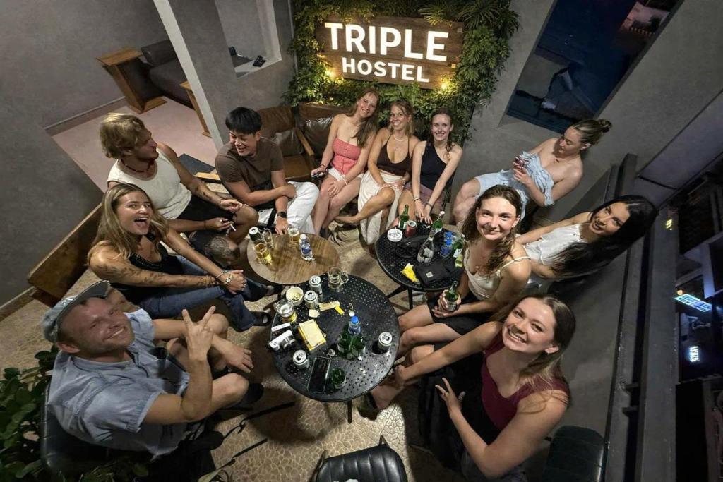 a group of people sitting around a table with a cake at Triple Hostel in Ho Chi Minh City
