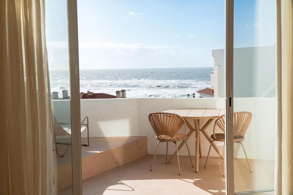 a balcony with a table and chairs and the ocean at Praia das Maçãs Sea view Retreat in Colares