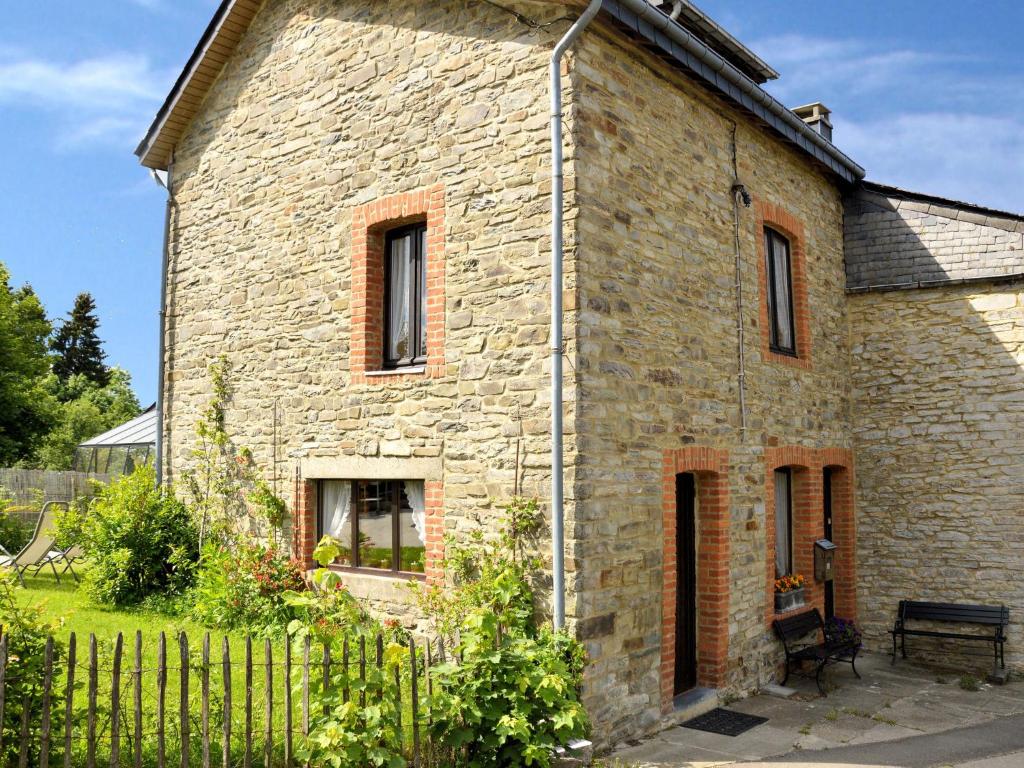 a stone house with a fence in front of it at Vintage Cottage with Shared Garden in Paliseul in Paliseul