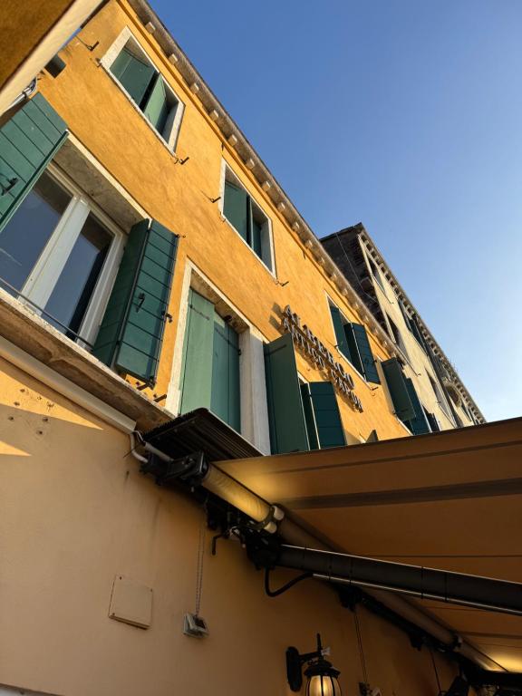 a building with green shuttered windows and awning at Experience Hotel Antico Capon in Venice