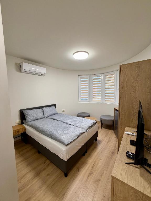 a bedroom with a bed and a desk with a television at Boutique Rooms Desi 3 in Pleven