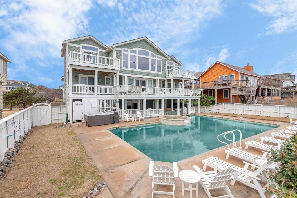 a large house with a swimming pool and chairs at 2869 - Seascape in Duck