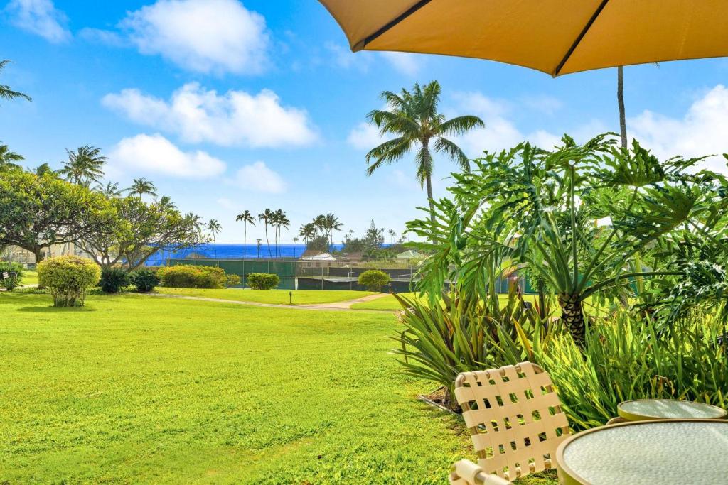 a table and chairs with an umbrella in a park at Kahala 312 in Kipu