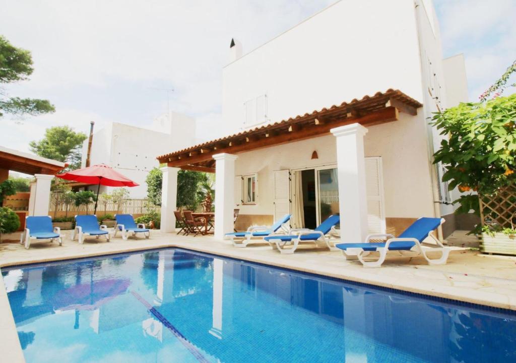 een zwembad met stoelen en een huis bij Villa Sofia in San Antonio