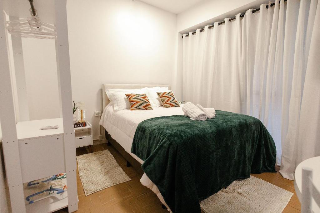 a bedroom with a bed with a green blanket at P&G Apto 202-San Gimignano in Caxias do Sul