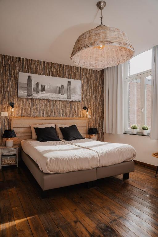 a bedroom with a large bed and a large chandelier at Cé La Vie in Maaseik