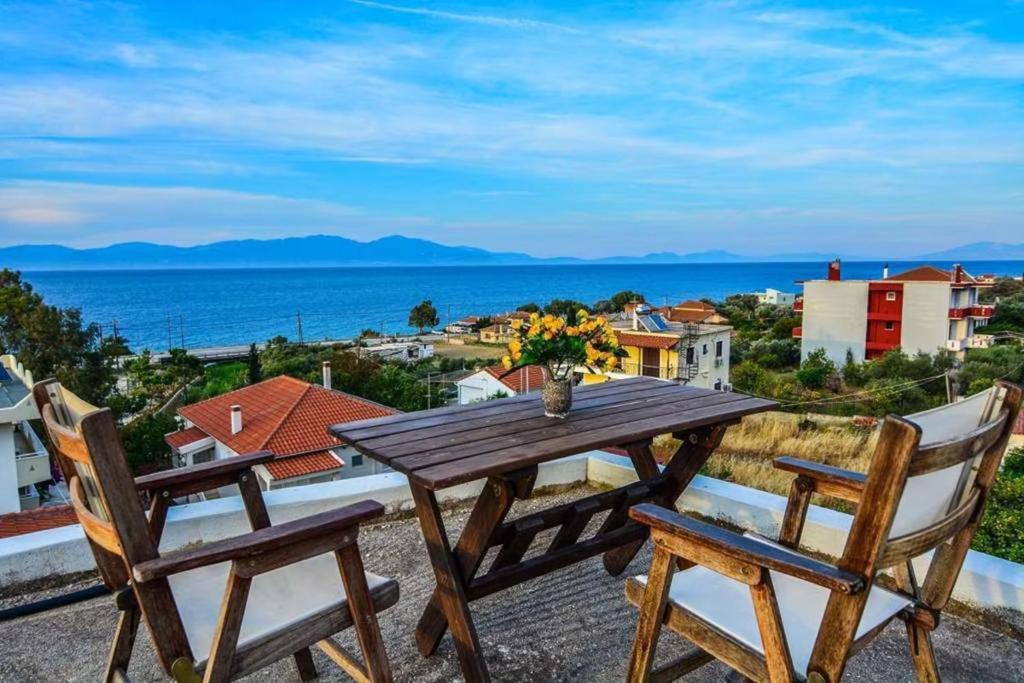a wooden table and chairs on a balcony with the ocean at White Villa in Xylokastro