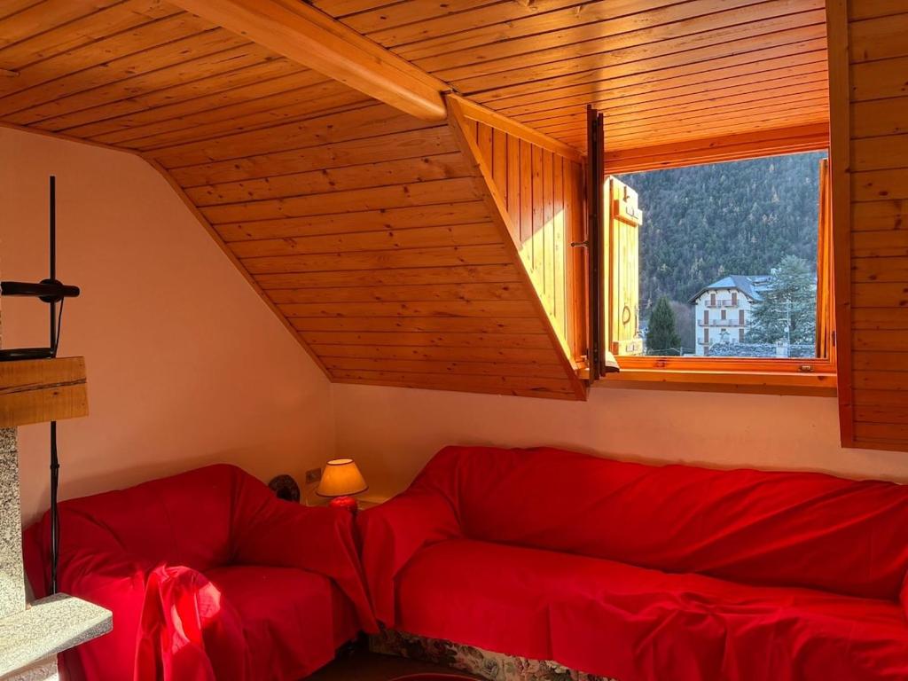 a living room with a red couch and a window at La mansarda in Santa Maria Maggiore